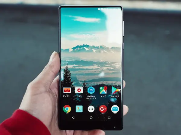 Hand holding an Android phone showing its home screen