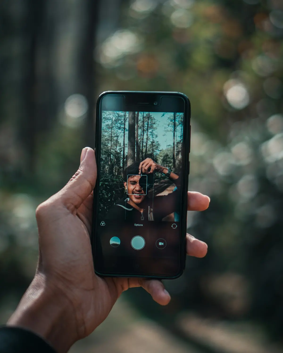 Phone screen showing a portrait of a photographer in a forest