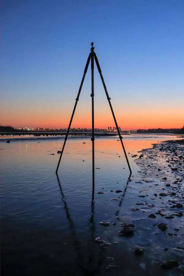Tripod standing in shallow water at sunset